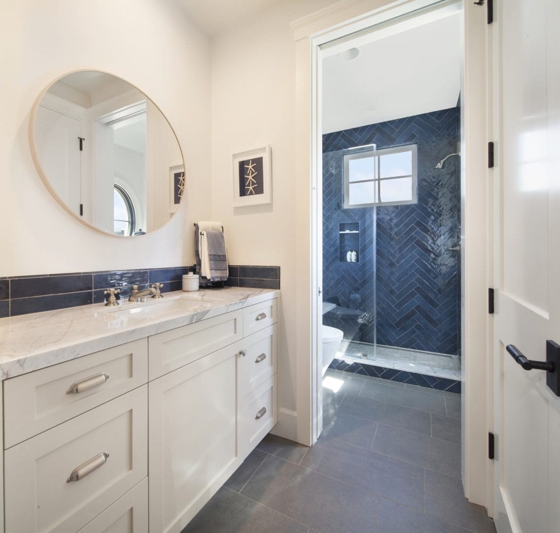 Round mirror above the wash area with off white cupboards