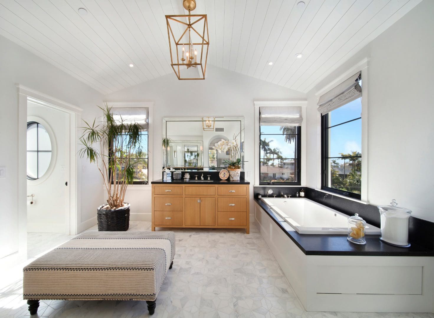 Bathtub beside the rectangle mirror and wooden cupboards