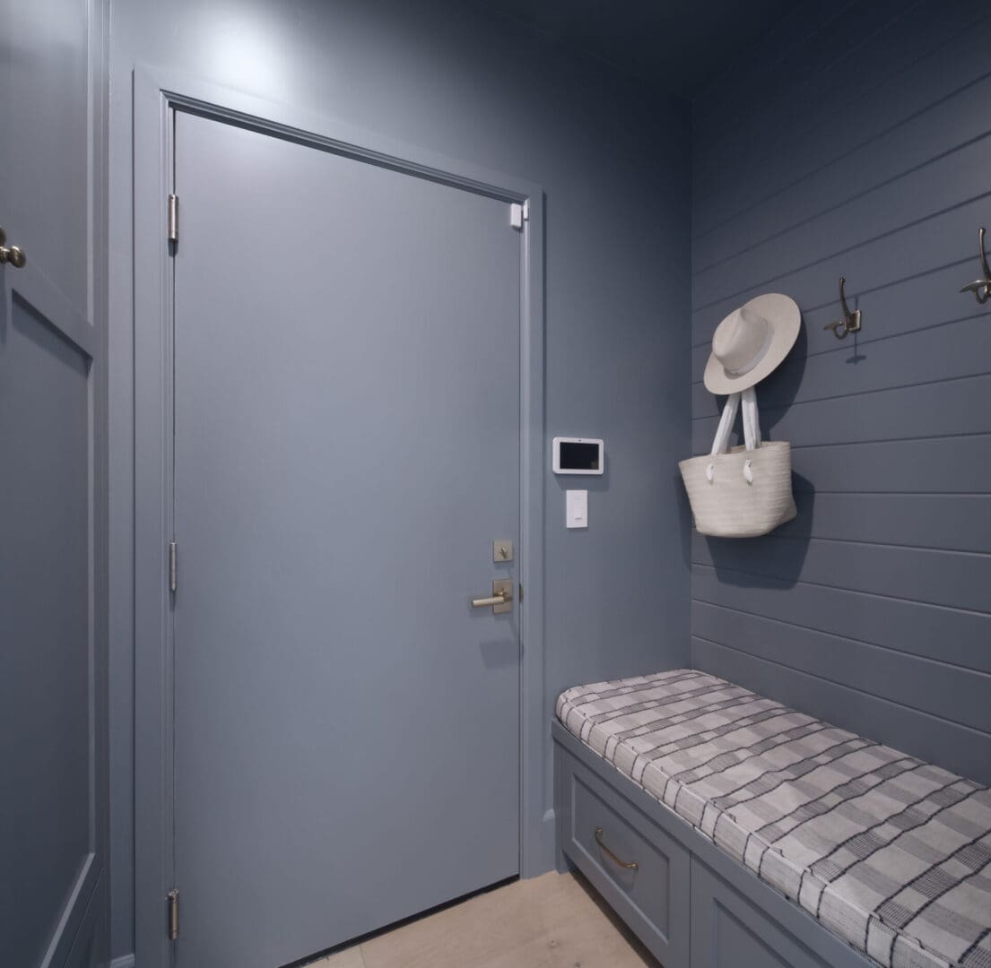 A blue mudroom with a bench and coat hooks.