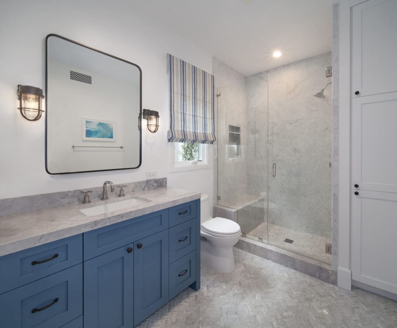 A bathroom with blue cabinets and a walk in shower.