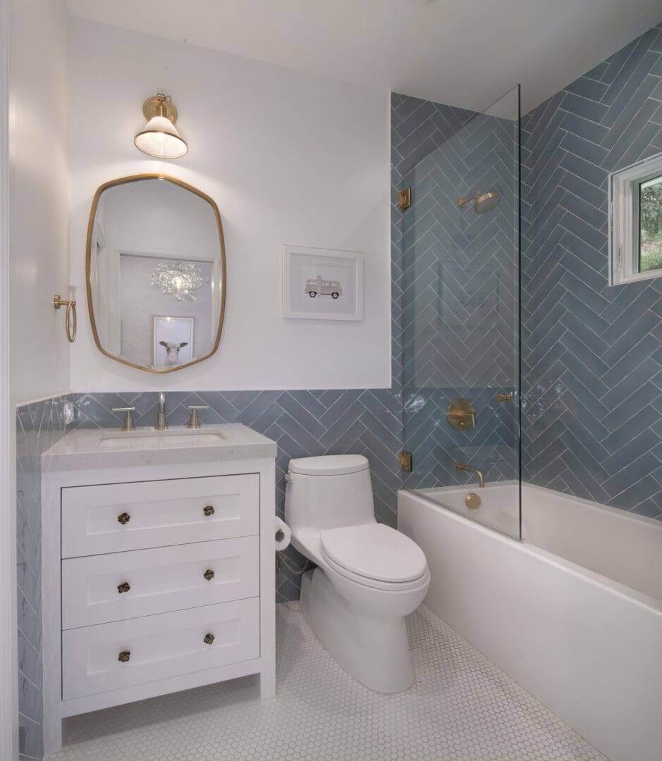 A bathroom with blue tile and gold fixtures.