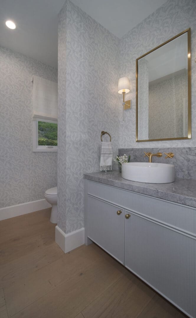 A bathroom with a white sink and white wallpaper.