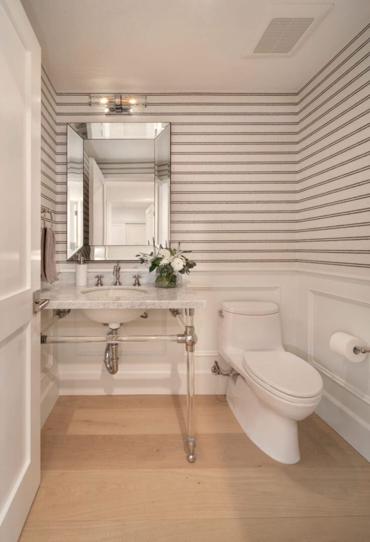 A white bathroom with striped walls and a toilet.