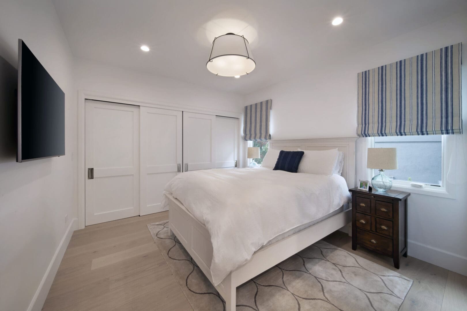 A white bedroom with a bed and a tv.