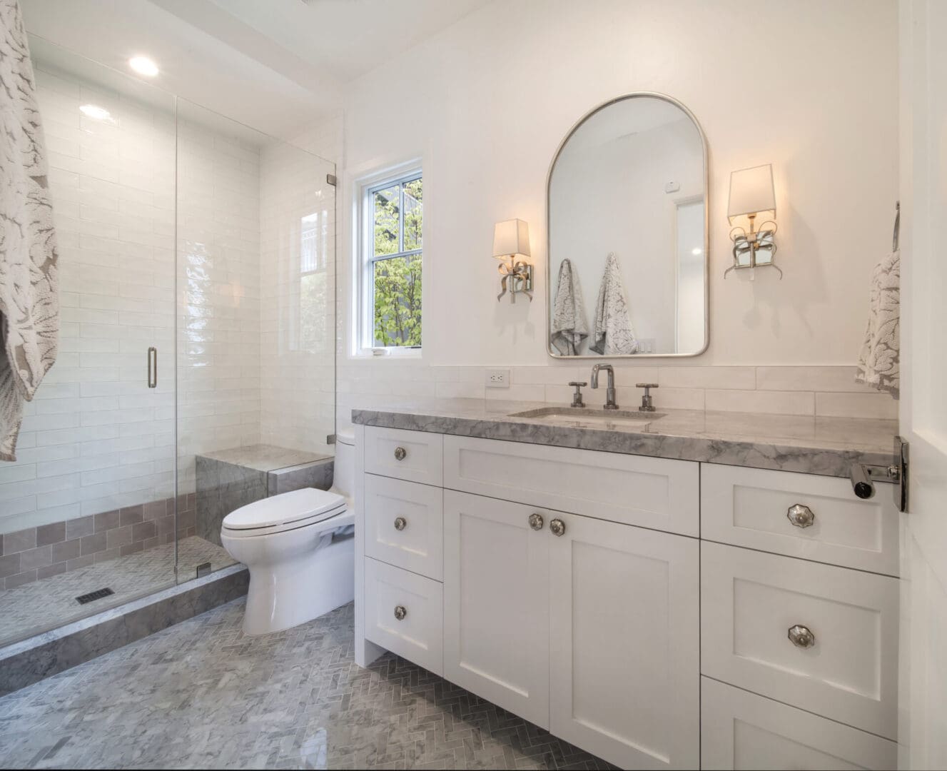 A white bathroom with marble counter tops and a walk in shower.